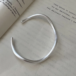 Minimalist S925 sterling silver cuff bracelet with matte wavy texture on a vintage book