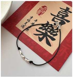 Detail of minimalist black cord bracelet with three silver metallic beads and lobster clasp