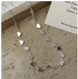Macro detail of S925 silver heart charm necklace with matte texture on grey stone