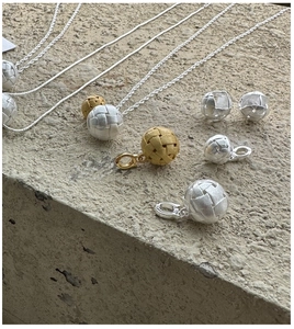 Detailed macro view of silver and gold woven ball pendant necklace and earring set