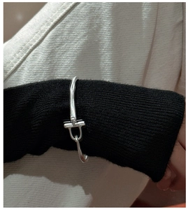 Vue détaillée d'un bracelet jonc argenté à boucle fer à cheval sur une manche en maille