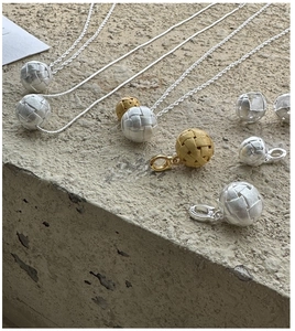Détails macro des pendentifs boules tissées en argent S925 et or sur béton moderne