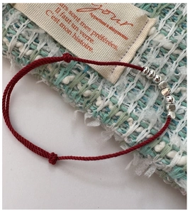 Detailed close-up of s925 silver beads on a braided red rope bracelet with adjustable knot