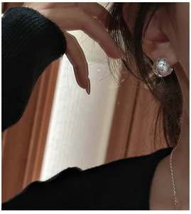 Detail of S925 sterling silver woven mesh ball earrings worn with elegant black knitwear