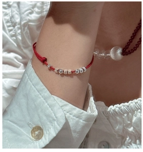 Detail of s925 silver beads on minimalist red braided cord bracelet worn on wrist