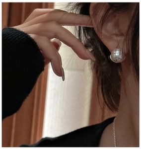 Close-up of S925 silver earring with intricate woven texture shown on a female ear model
