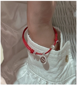 Detail of s925 silver lucky red rope bracelet with Good Luck charm on wrist