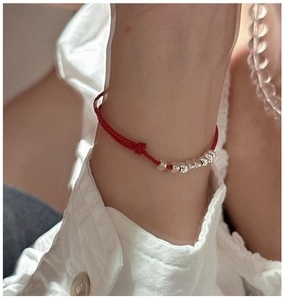 Detail of red cord bracelet with silver beads on wrist with adjustable knot design