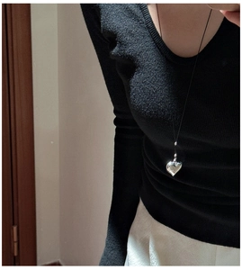 Close-up of minimalist S925 silver heart pendant on black cord worn by a model