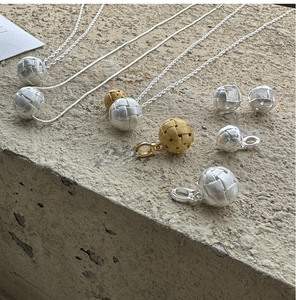 Detailopname van geweven bal sieradenset met zilveren en gouden matte metalen texturen
