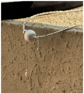 Détail macro d'une chaîne en argent S925 avec perle mate et pendentif en perle