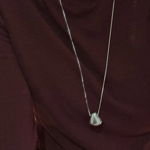 Minimalist S925 sterling silver bean pendant necklace with polished finish on red sweater