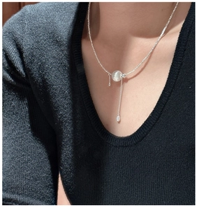 Gros plan d'un collier en argent 925 avec pendentif boule brossée et pompon sur un mannequin