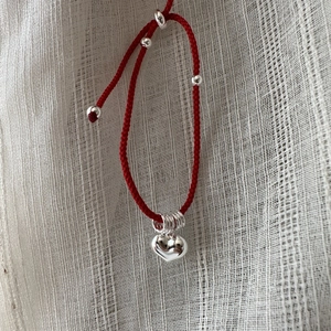 Minimalist red cord bracelet with polished silver heart pendant and adjustable knots
