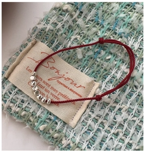 Detailed macro view of minimalist S925 silver beads on adjustable red braided rope bracelet