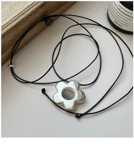 Détail d'un pendentif fleur creuse en argent 925 sur un collier en corde noire