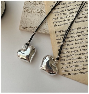 Detail of S925 sterling silver heart pendants with polished finish and black cord necklace