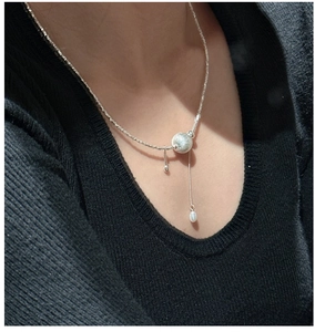 Détail macro du collier en argent 925 avec boule brossée et perle baroque portée sur modèle