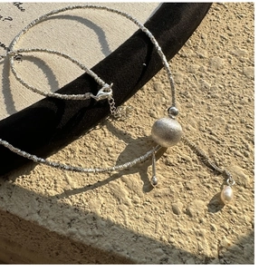 Vue détaillée de la sphère argentée mate et de la perle sur le collier à pépites irrégulières