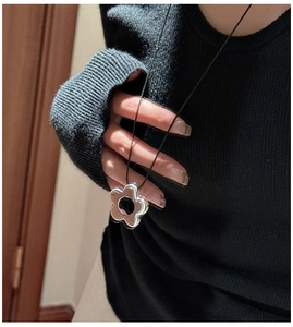 Gros plan détaillé du pendentif fleur en argent 925 avec centre noir sur un pull en maille