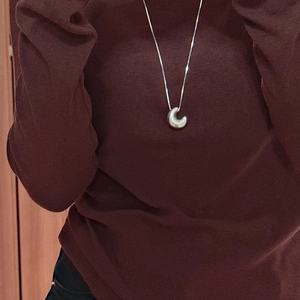 Elegant silver bean pendant necklace on red sweater for a minimalist fashion look