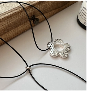 Détail d'un pendentif fleur en argent 925 avec un cordon en cire noire ajustable