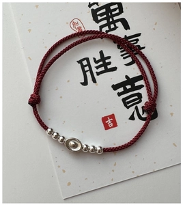 Close-up of red woven bracelet with silver sycee charm and beads on festive card
