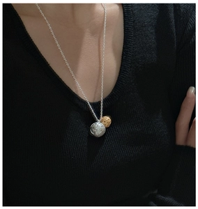 Détail du collier pendentif globe en argent S925 avec contraste doré et argenté sur pull