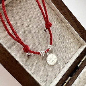 S925 sterling silver red string bracelet with Good Luck charm on beige jewelry box