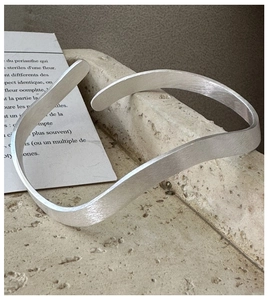 Detail of S925 sterling silver bangle featuring wave textures and matte brushed finish