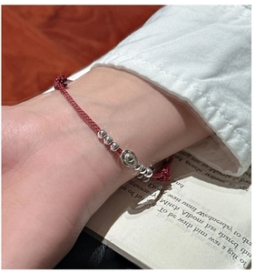 Close-up of S925 sterling silver yuanbao charm on a red braided rope bracelet