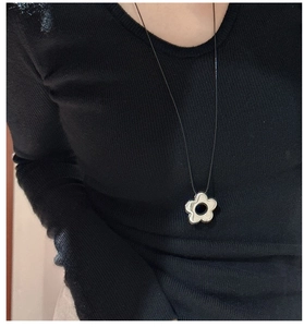 Détail d'un pendentif fleur en argent 925 sur un collier en cordon noir élégant