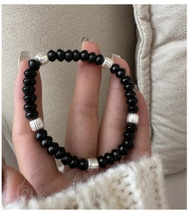 Detail of beaded bracelet with black polished beads and silver textured metal spacers