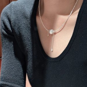 Collier en argent 925 avec pendentif boule givrée et pompon porté par un mannequin femme
