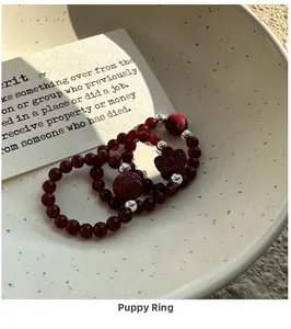 Detail of S925 silver red agate beaded rings set with intricate carvings in a ceramic bowl
