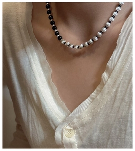 Detail of silver brushed beads and black round beads on a minimalist necklace
