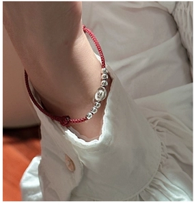 Close-up of minimalist red cord bracelet with S925 silver ingots and beads on wrist
