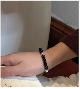 Detailed view of deep red beaded bracelet with textured silver spacers on a wrist