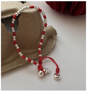 Détail du bracelet tressé rouge avec perles argentées et pendentif gourde en argent