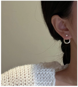 Detail of S925 sterling silver ball stud and thick hoop earring on model ear