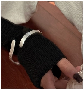 Minimalist silver wave texture bracelet styled over a black knit sleeve for winter fashion