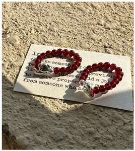 Détail de bagues en perles d'agate rouge avec breloques teckel en argent S925 et cordon