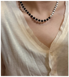 Detail of S925 silver and black onyx beaded necklace on a model with beige knitwear