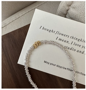 Detail of S925 silver coiled chain bracelet featuring handcrafted golden cube beads