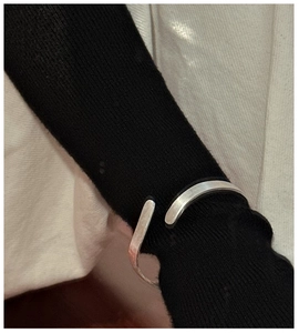 Polished silver cuff bracelet featuring wave texture worn over a black sweater sleeve