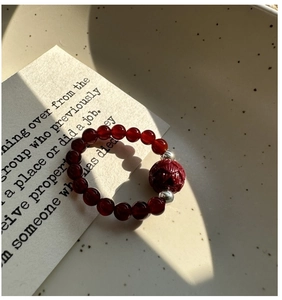 Macro detail of elastic ring featuring a red carved bead and natural red agate beads