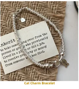 Macro detail of S925 silver beaded bracelet featuring cat, fish bone and heart charms