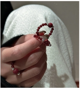 Macro detail of red agate bead rings featuring floral charms and stretch rope design