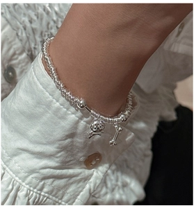 Close-up of S925 sterling silver beaded bracelet with puppy and bone charms on wrist