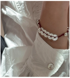 Détail du bracelet en soie rouge avec pièces en argent S925 sur poignet